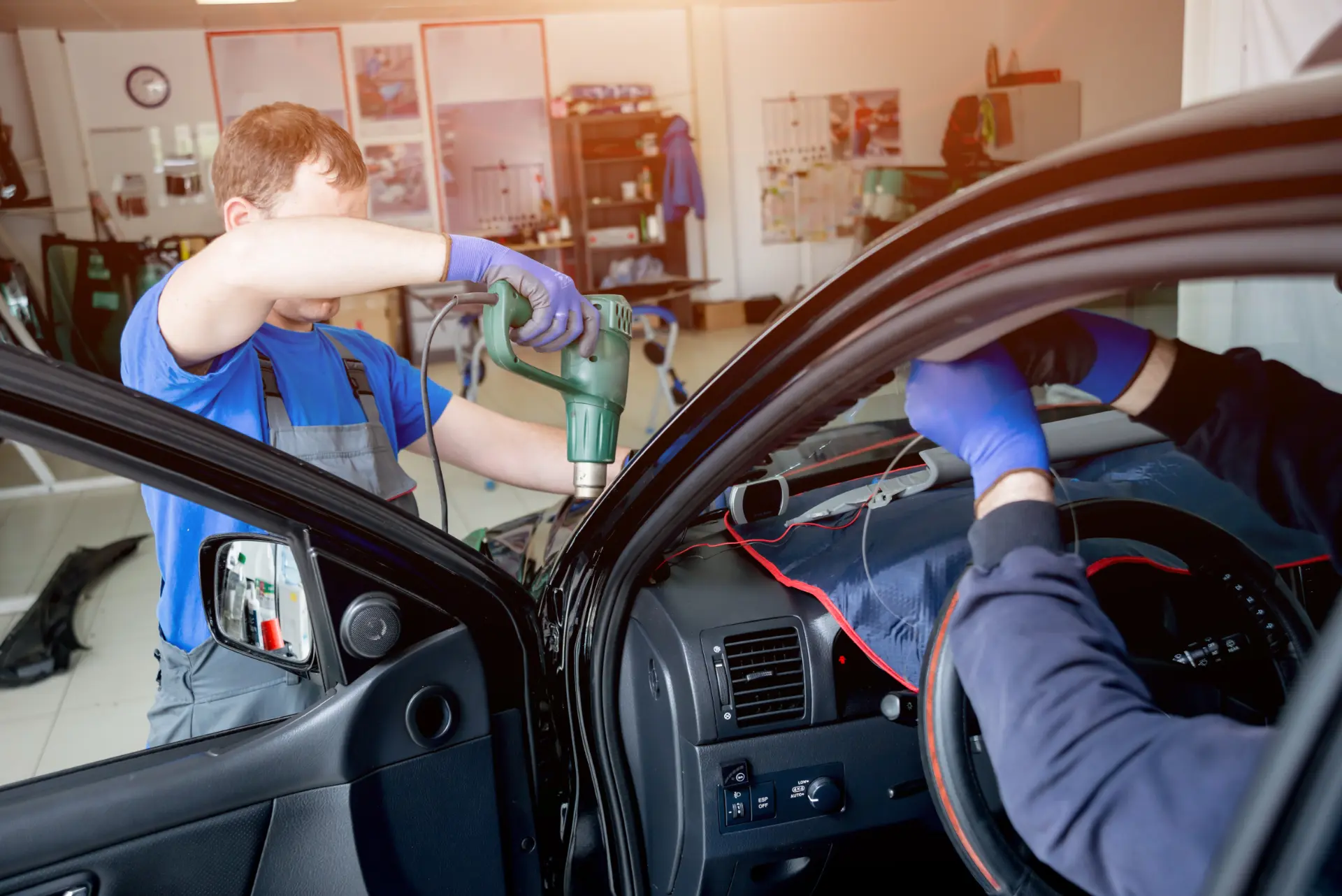 Technician using a heat gun to remove car window tint film