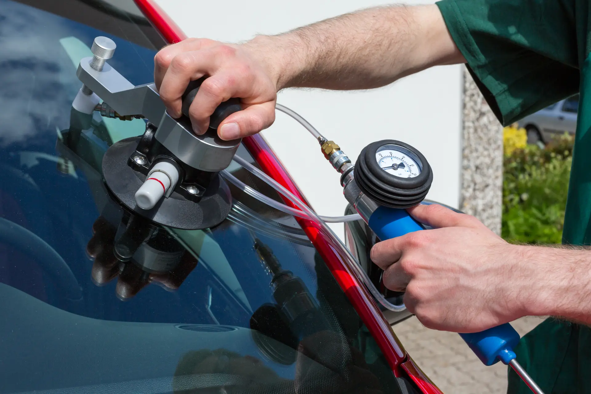 Technician using a vacuum pressure pump for a windscreen chip repair